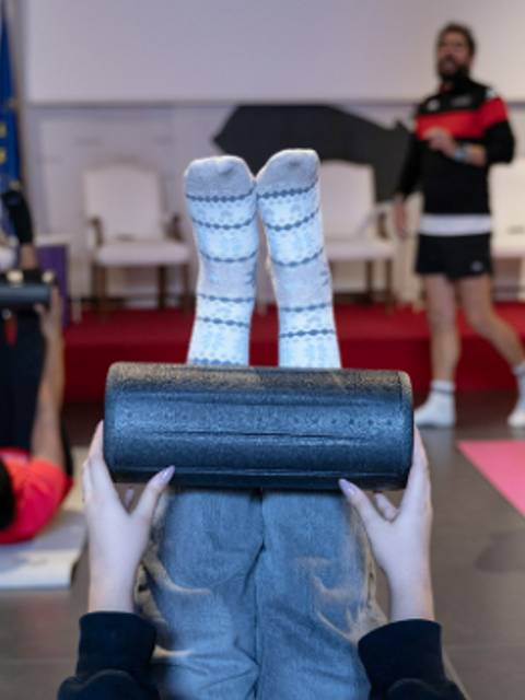 Un grupo de personas realizando ejercicios de entrenamiento físico con rodillos de espuma.