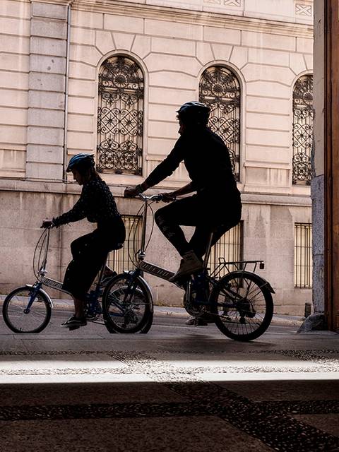 Siluetas de dos personas montando en bicicletas en un umbral de una puerta.