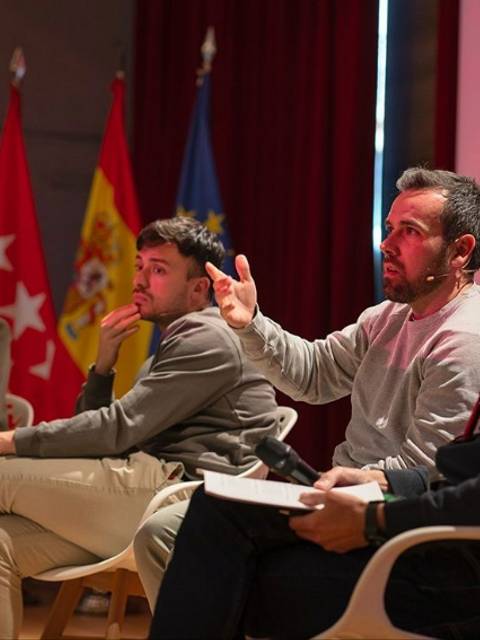 Un panel de discusión con varias personas sentadas en sillas, conversando sobre un tema en un escenario.