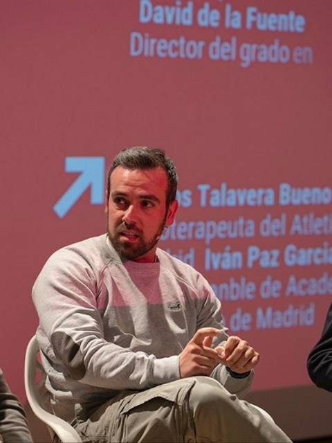 Una mesa redonda con tres ponentes discutiendo sobre temas relacionados con el deporte, con un fondo de presentación en rojo.