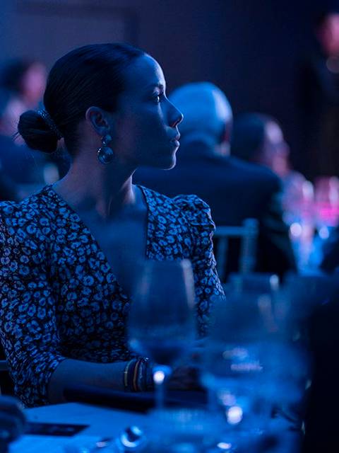 Una mujer observa atentamente en un evento nocturno iluminado con luces azules.