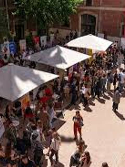 Una multitud de personas se congrega en un evento al aire libre bajo varias carpas.