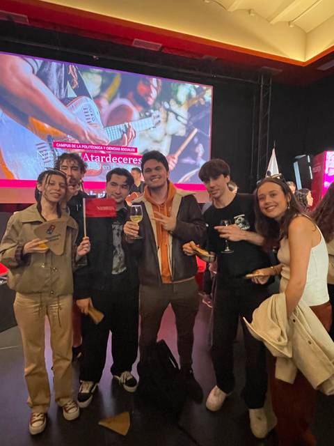 Grupo de jóvenes posando en un evento con cartas de presentación en las manos.