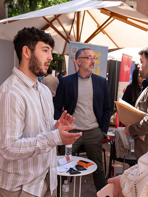 Una feria de empleo donde jóvenes interactúan con representantes de empresas.