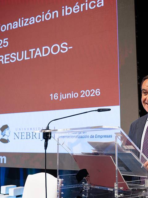 Un hombre sonriente presenta un informe sobre la internacionalización ibérica en un evento académico.