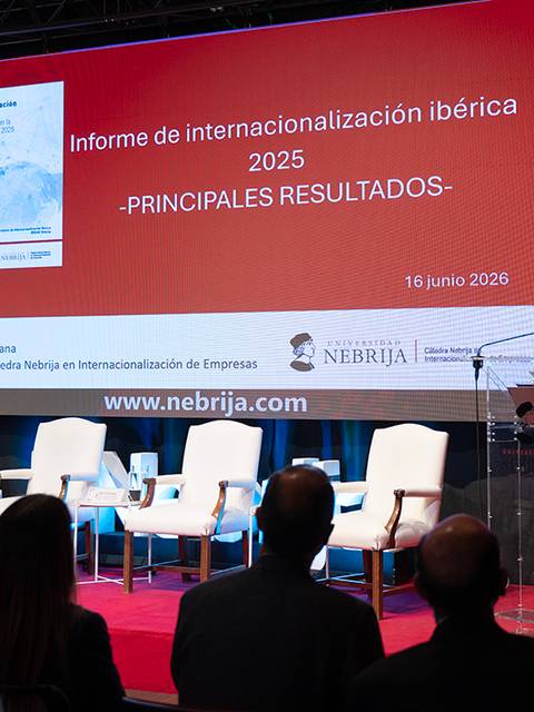 Un presentador expone el informe de internacionalización ibérica 2025 en un evento con banderas y un público atento.
