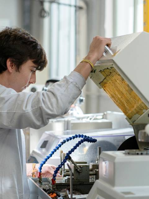 Un joven en un laboratorio está manipulando un equipo técnico con un aspecto concentrado.