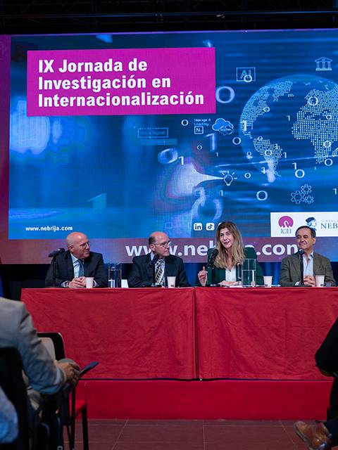 Un panel de discusión en la IX Jornada de Investigación en Internacionalización con varios ponentes en un escenario.