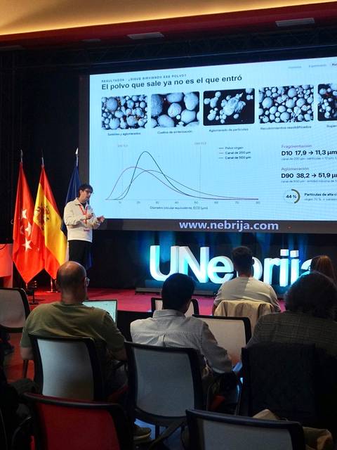Un ponente presenta un tema con apoyo visual frente a una audiencia en un evento académico.