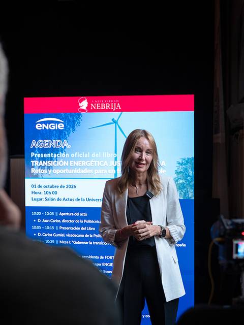 Una mujer habla frente a un grupo de personas durante un evento relacionado con la energía sostenible.