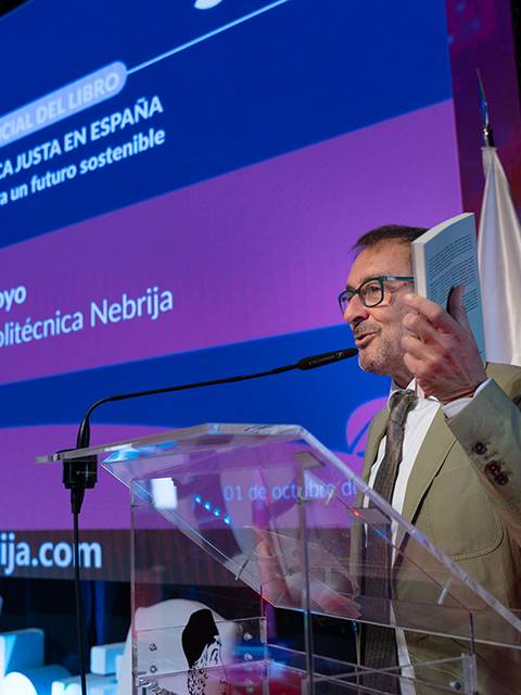 Un hombre de pie presenta un libro en un evento relacionado con la energía sostenible.