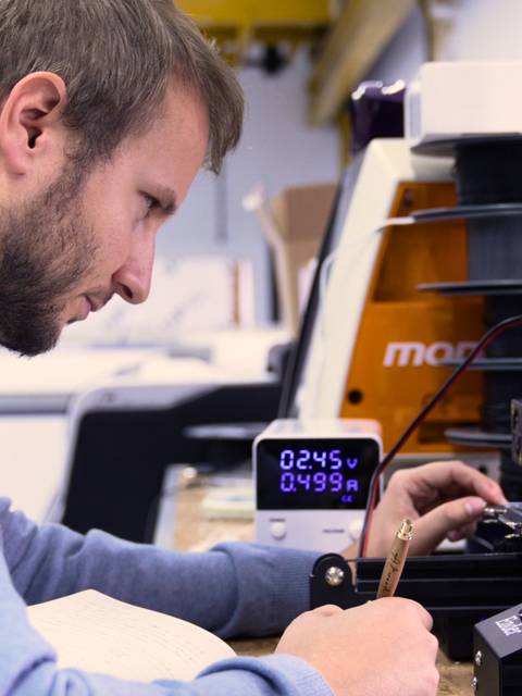 Un hombre trabaja en una impresora 3D en un entorno técnico.