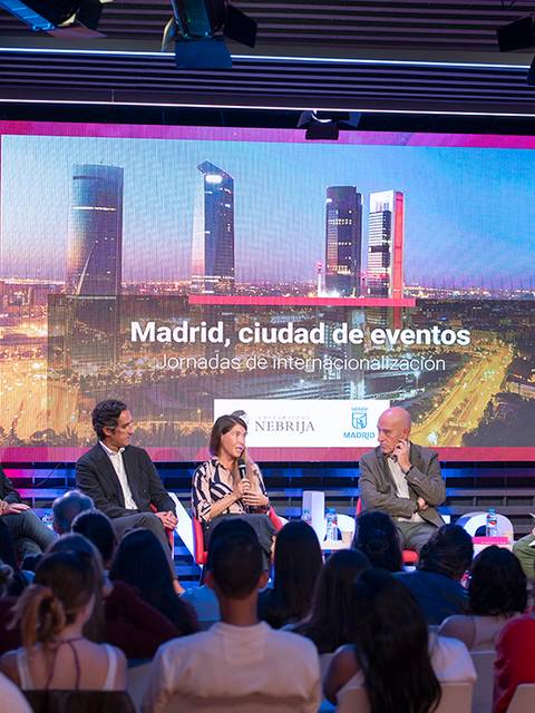 Un panel de discusión sobre Madrid como ciudad de eventos, con varios ponentes y una presentación de fondo.