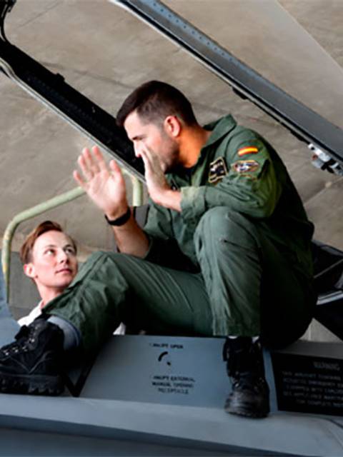 Dos pilotos conversan cerca de un avión de combate.
