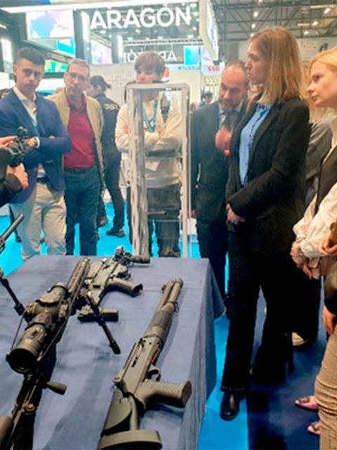 Un grupo de personas observa a un policía que presenta armas en una exhibición.