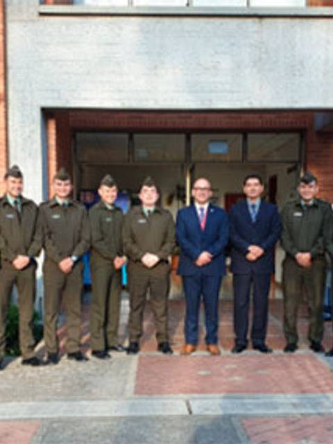 Un grupo de oficiales en uniforme posan frente a un edificio institucional.