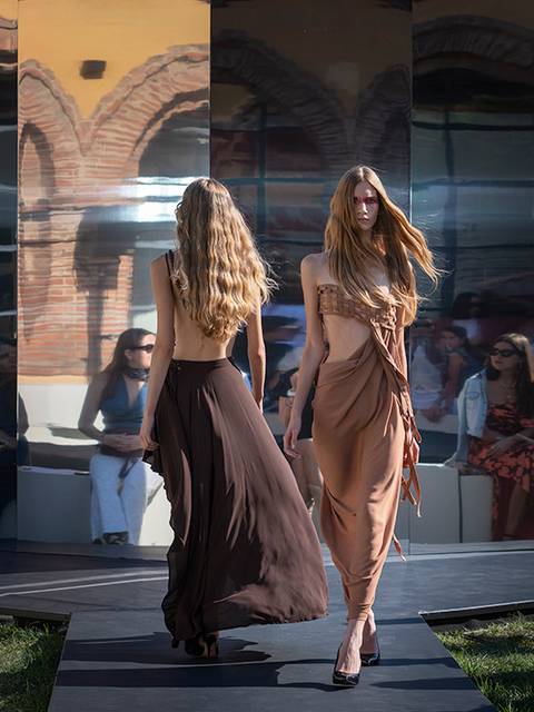 Dos modelos caminan por una pasarela durante un desfile de moda al aire libre.