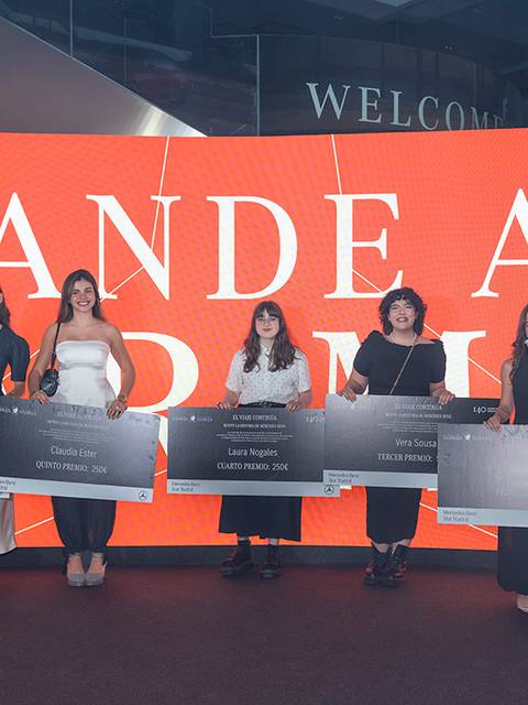 Un grupo de seis personas posando con grandes cheques frente a una pantalla que dice 'GRANDE ARRÉGLATE'.