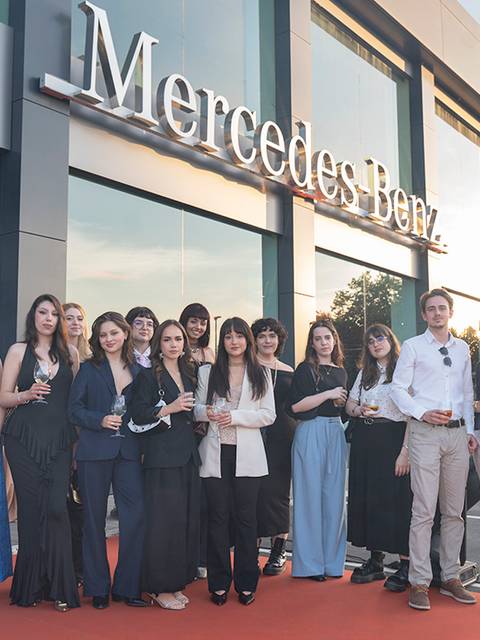 Un grupo de personas posando frente a un concesionario de Mercedes-Benz.