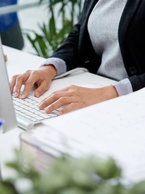 Una persona trabajando en una computadora en un entorno de oficina.