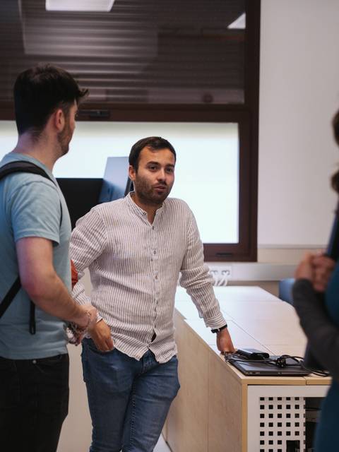 Tres personas conversan en un entorno de oficina moderna.