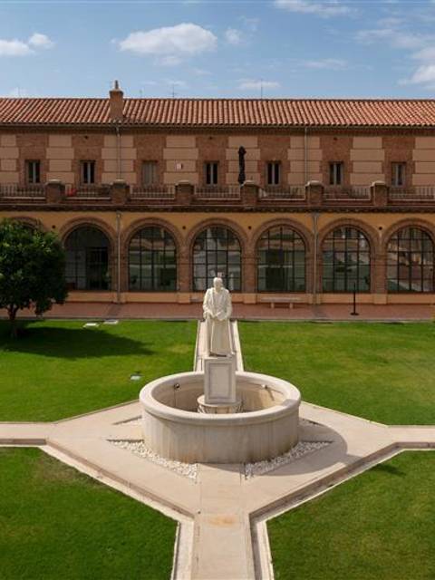 Vista de un patio interior con una estatua en el centro y edificios de fondo.