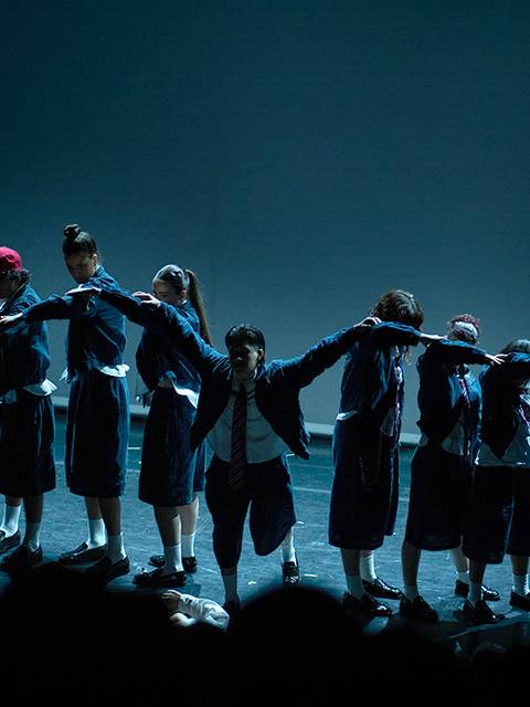 Un grupo de bailarines en una actuación en escena, formando una línea con poses coordinadas.