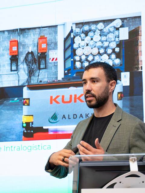 Un presentador habla sobre soluciones de intralogística en un entorno industrial.