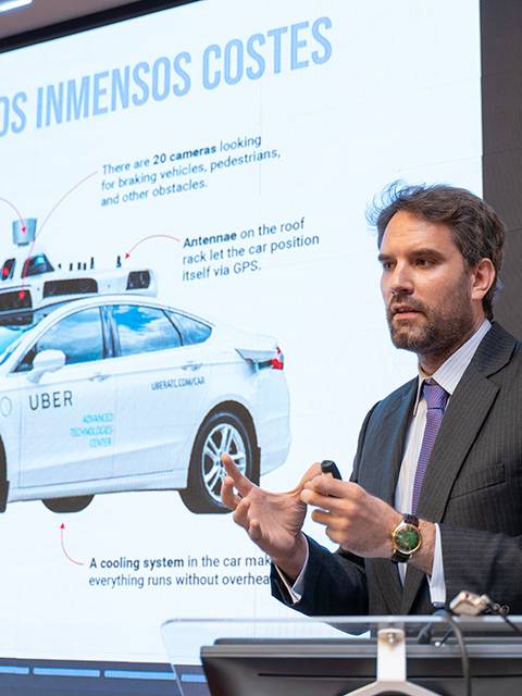 Un presentador habla sobre las características de un vehículo autónomo de Uber mientras se proyecta una diapositiva informativa.