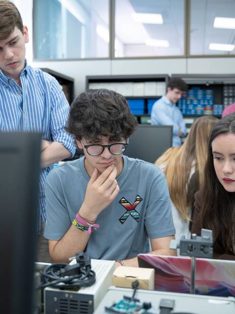Un grupo de estudiantes trabaja en un proyecto en un aula, concentrados en sus computadoras.