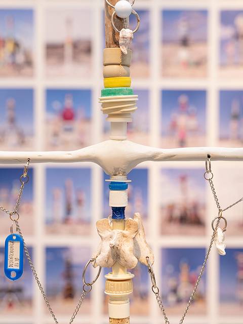 Una escultura de balanza con elementos decorativos frente a un fondo de fotografías.