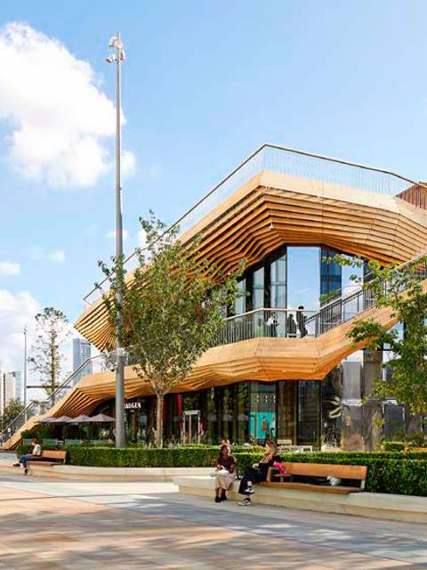 Edificio moderno con diseño arquitectónico distintivo rodeado de áreas verdes y un espacio público.