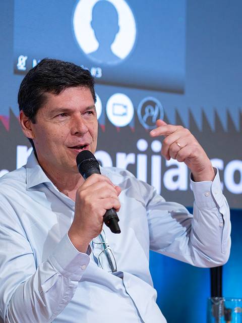 Un hombre sostiene un micrófono mientras habla en un evento.