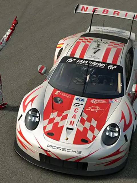 Un piloto celebra su victoria junto a un coche de carreras Porsche con un diseño distintivo en una pista.