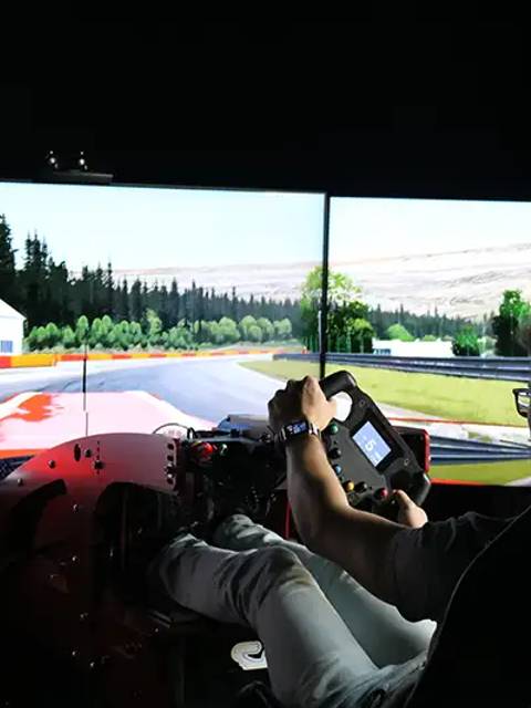Una persona está conduciendo un simulador de carreras en un entorno virtual de pista.