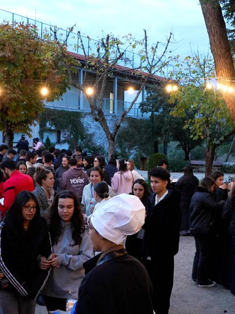 Una multitud de personas se congrega en un ambiente al aire libre, con luces y árboles alrededor.