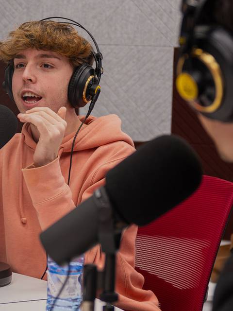 Un joven está participando en un podcast, hablando y gesticulando con entusiasmo.