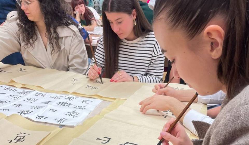 Un grupo de personas practica caligrafía sobre papel.