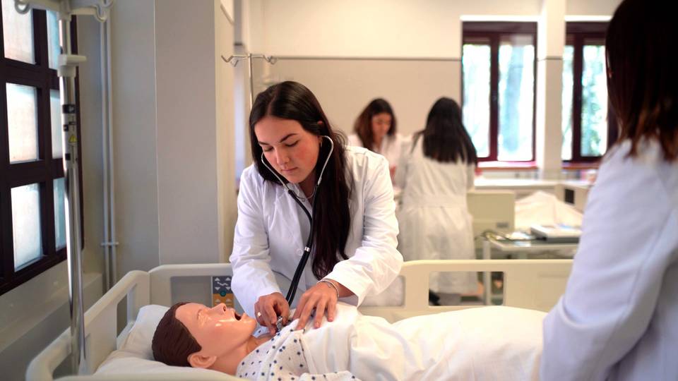 Una estudiante de medicina está atendiendo a un maniquí en un entorno clínico.
