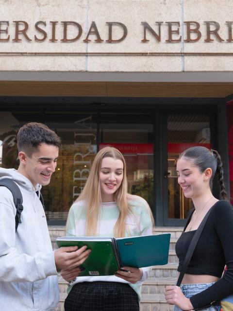 Tres estudiantes interactúan frente a la Universidad Nebrija.