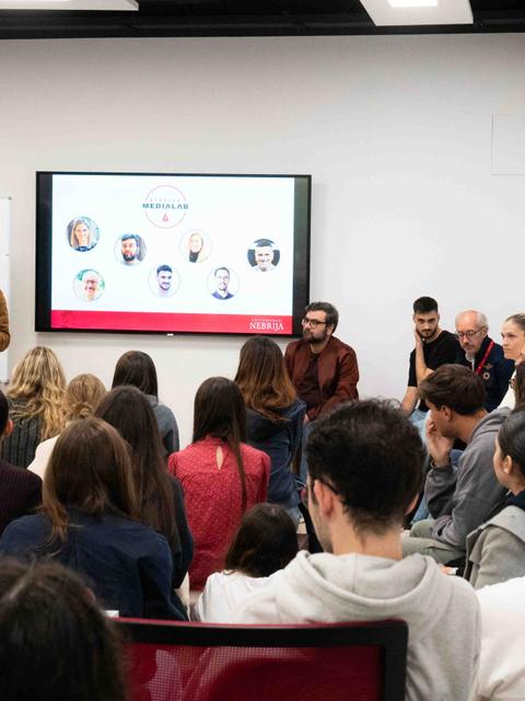 Una presentación en un espacio académico con un ponente frente a un público atento.