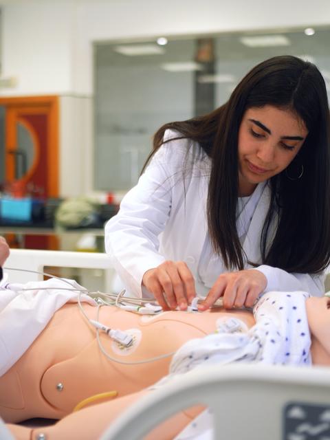 Una estudiante está practicando en un maniquí médico en un entorno de simulación clínica.