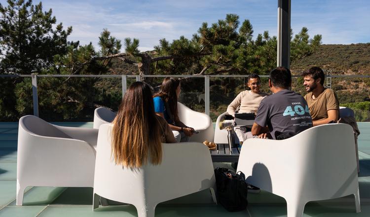Varias personas conversando en un ambiente al aire libre con asientos modernos.