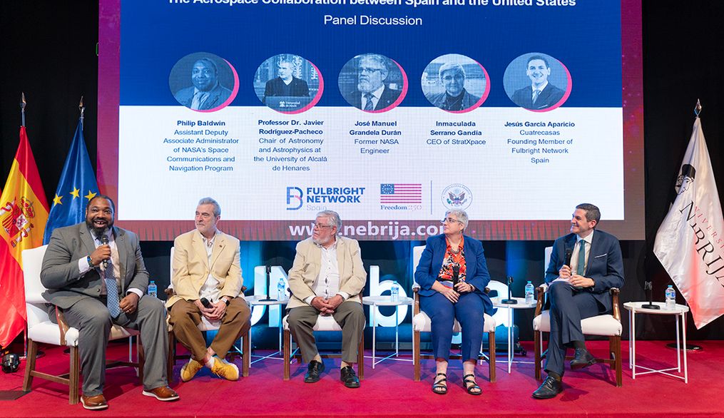 Panel de discusión sobre la colaboración aeroespacial entre España y Estados Unidos con cinco ponentes en el escenario.