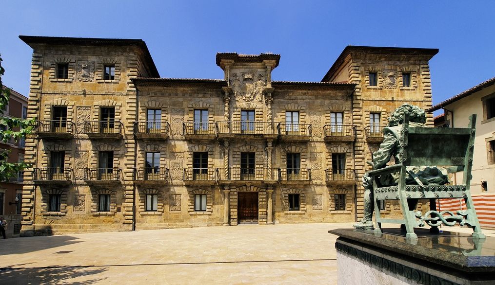 Una fachada de un edificio histórico con detalles arquitectónicos en piedra y un patio amplio.