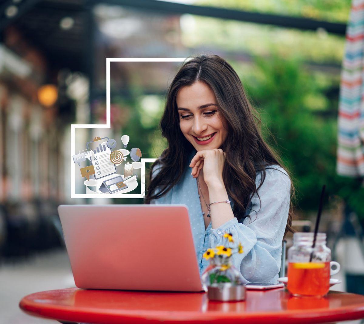 Una mujer sonriente trabaja en su laptop mientras toma una bebida en una mesa al aire libre.
