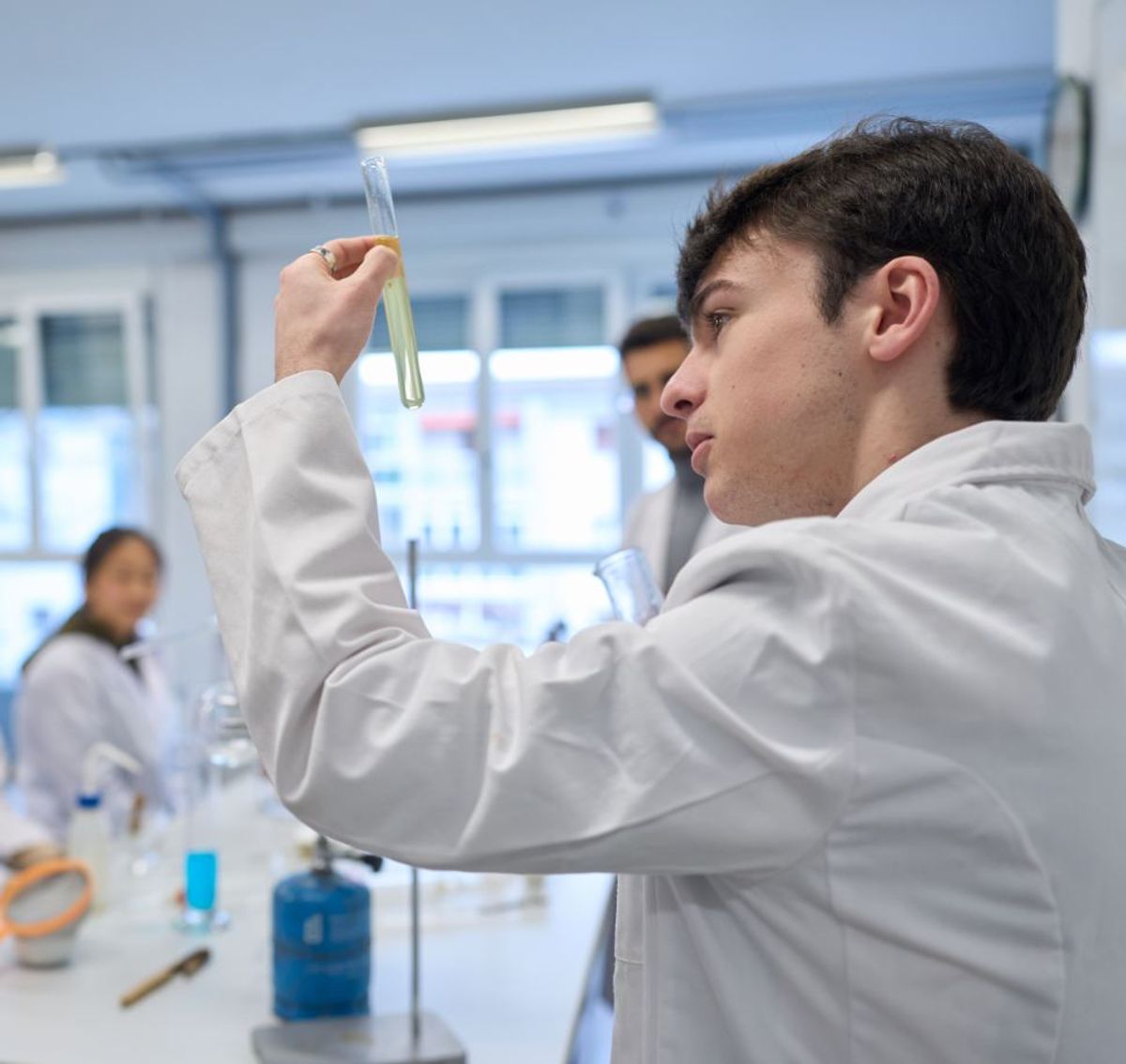 Un grupo de estudiantes de laboratorio observa una prueba científica en un tubo de ensayo.
