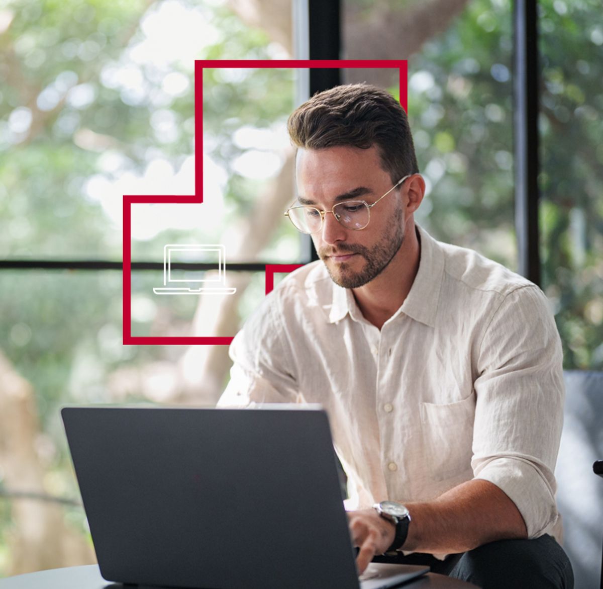 Un hombre trabaja en su computadora portátil en un ambiente luminoso y natural.