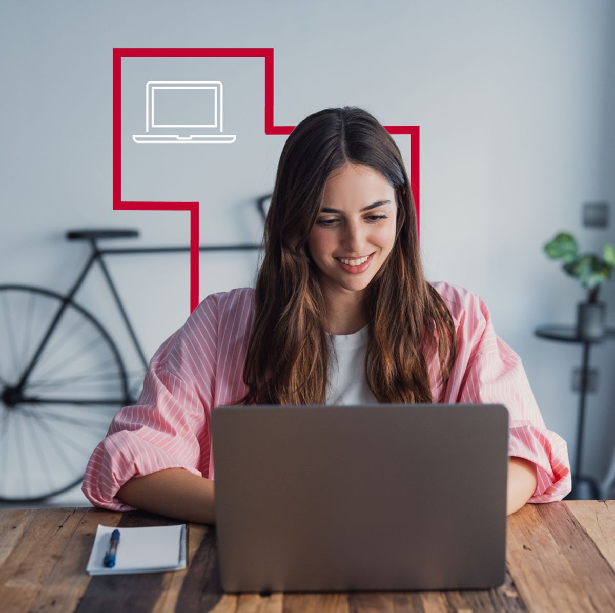 Una mujer sonriente trabaja en su laptop frente a una pared con un diseño moderno.