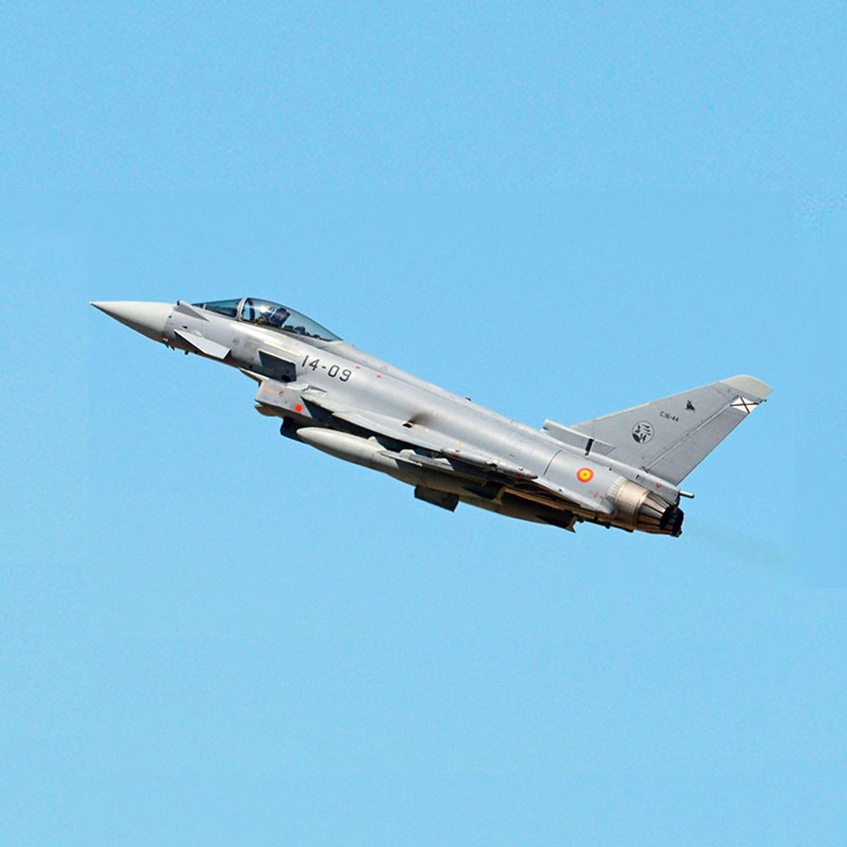 Un caza militar realizando un despegue en el cielo azul.